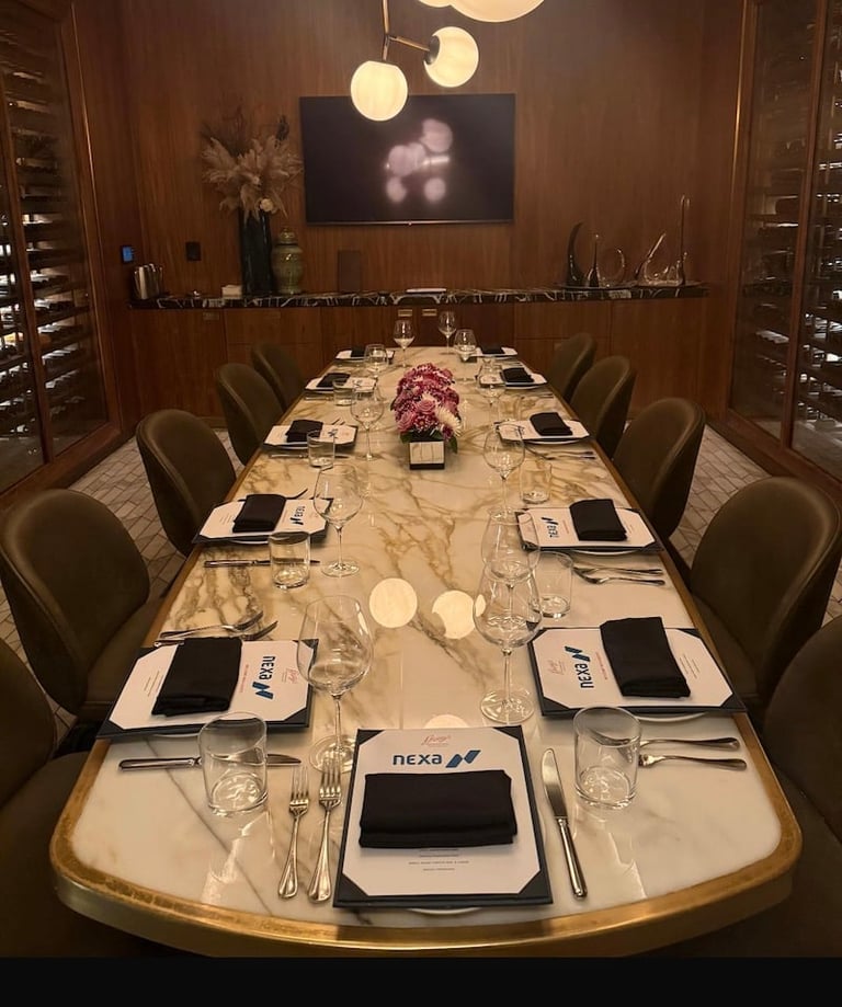 Elegant formal dining room with long marble table set with place settings, modern pendant lights, and wood-paneled walls